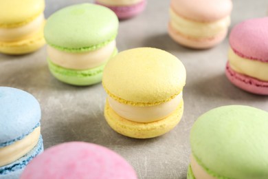 Many delicious colorful macarons on grey table, closeup