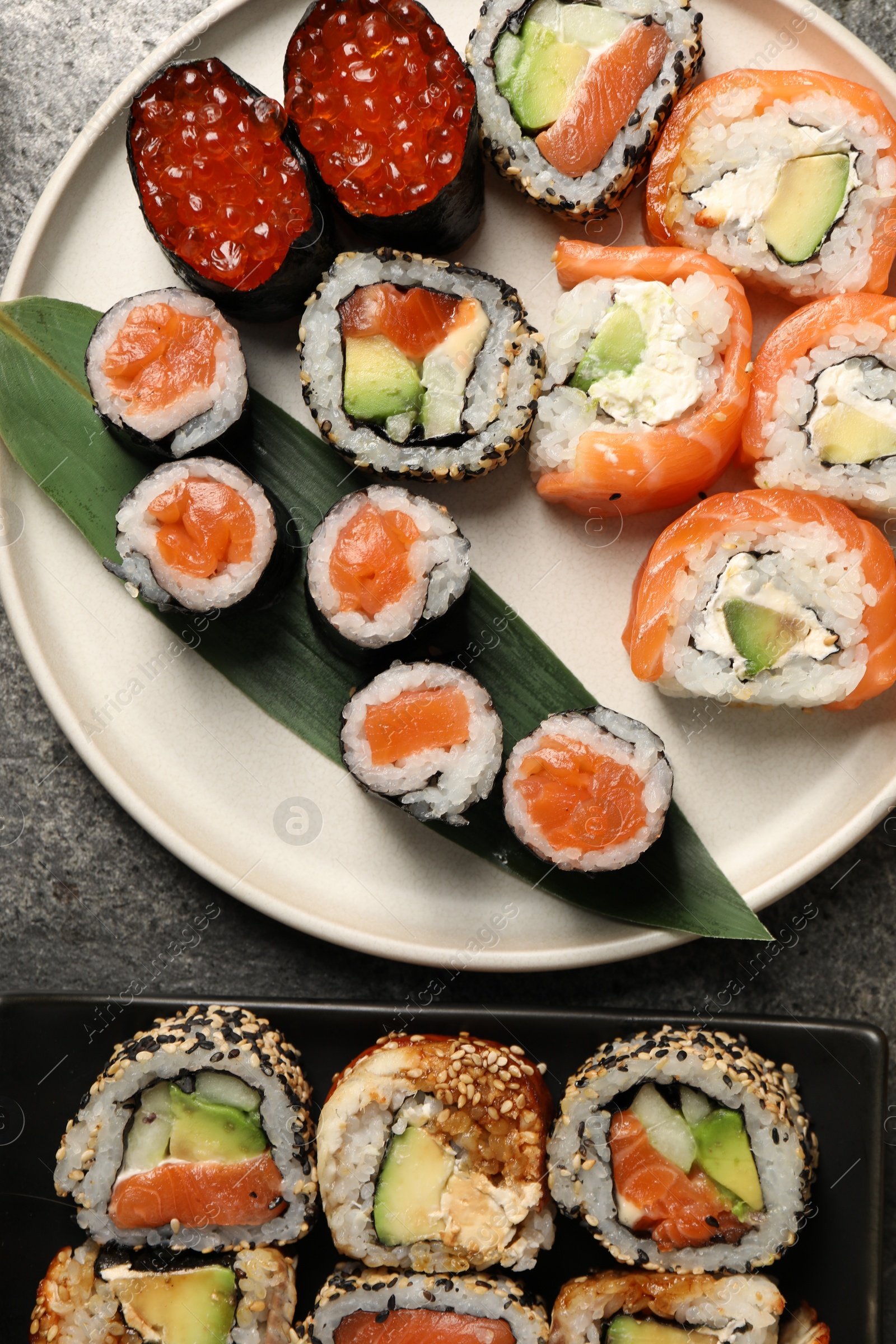 Photo of Delicious sushi rolls on grey table, flat lay