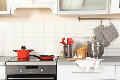 Photo of Set of clean cookware, utensils and products on table in modern kitchen