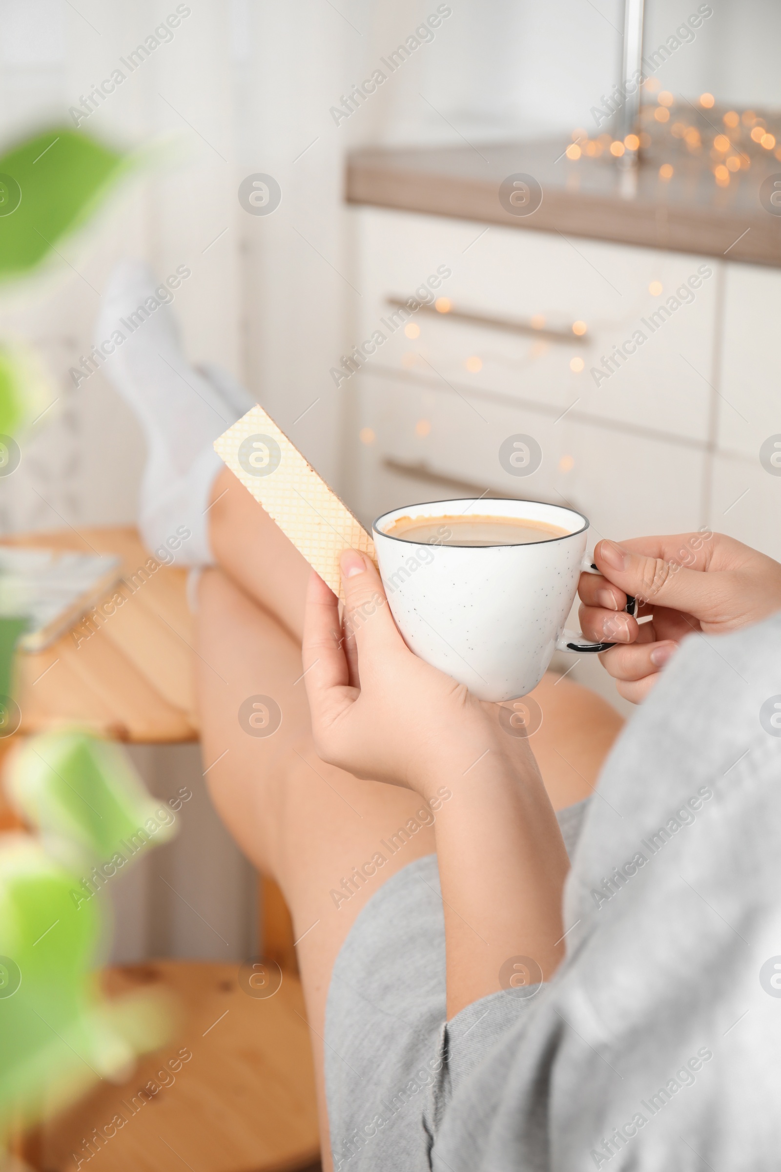 Photo of Woman having delicious wafer and coffee for breakfast indoors, closeup