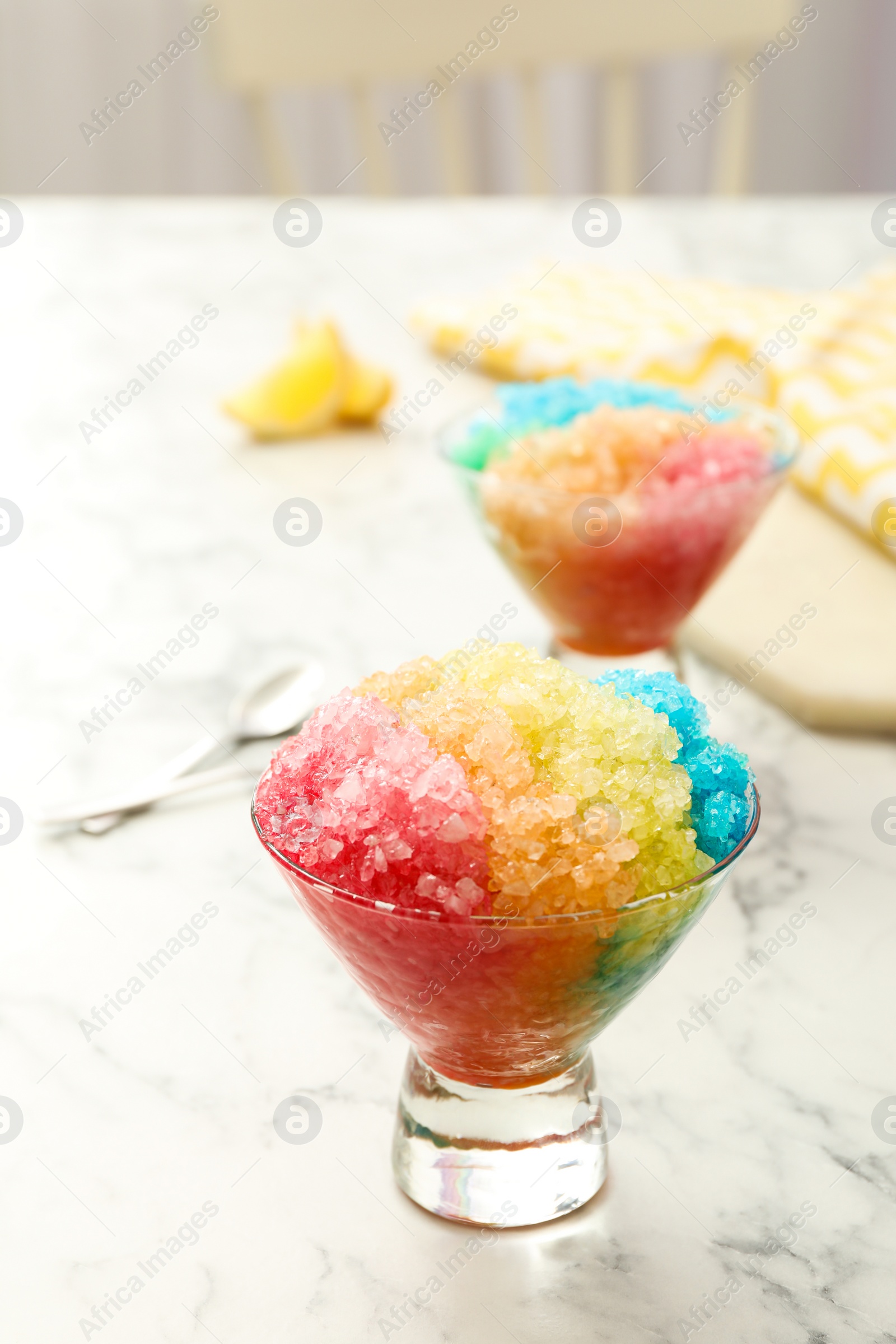 Photo of Rainbow shaving ice in glass dessert bowls on white marble table indoors