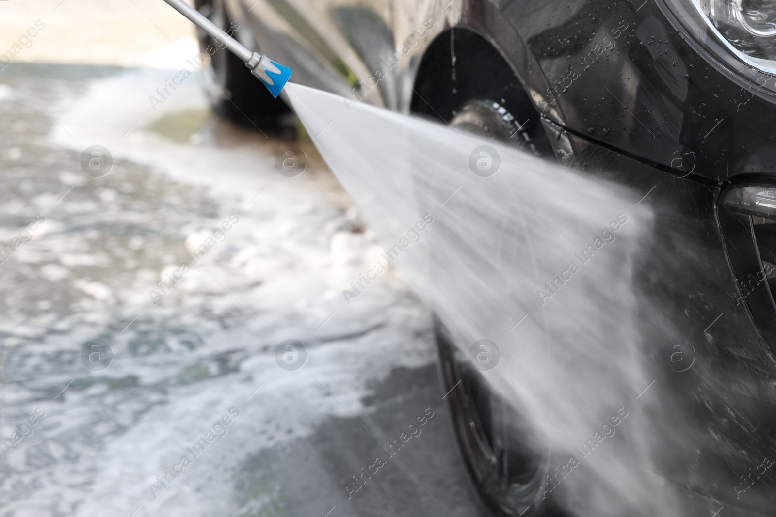 Photo of Washing auto with high pressure water jet at outdoor car wash, closeup