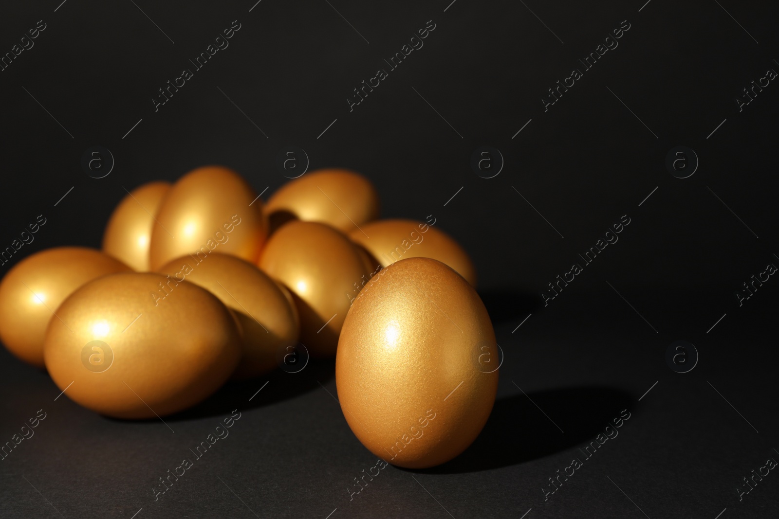 Photo of Many shiny golden eggs on black background. Space for text