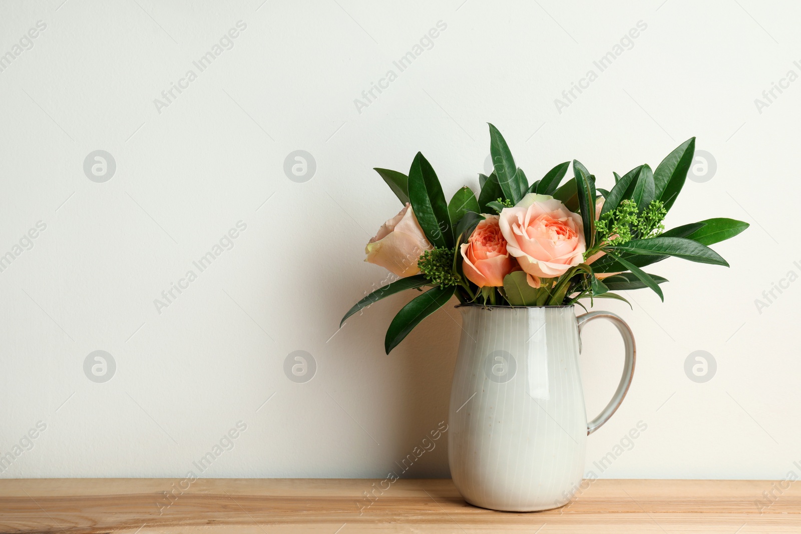 Photo of Bouquet of beautiful flowers in vase on wooden table against white background. Space for text