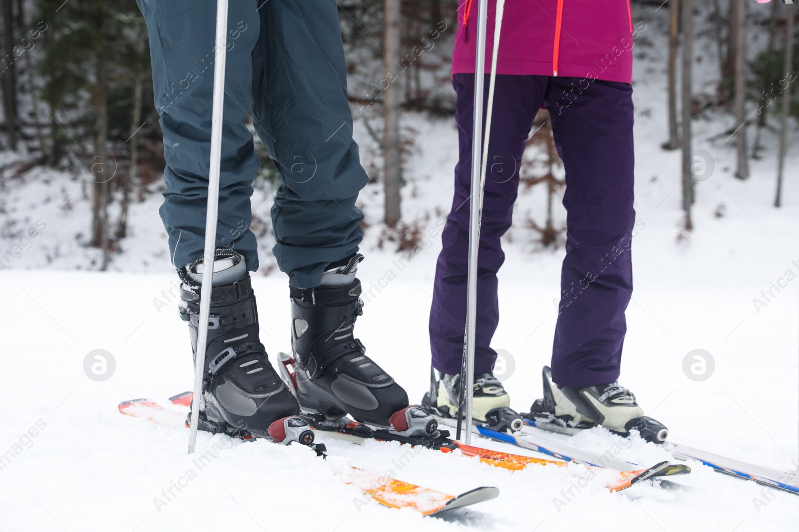 Photo of Couple of skiers on slope at resort, closeup. Winter vacation