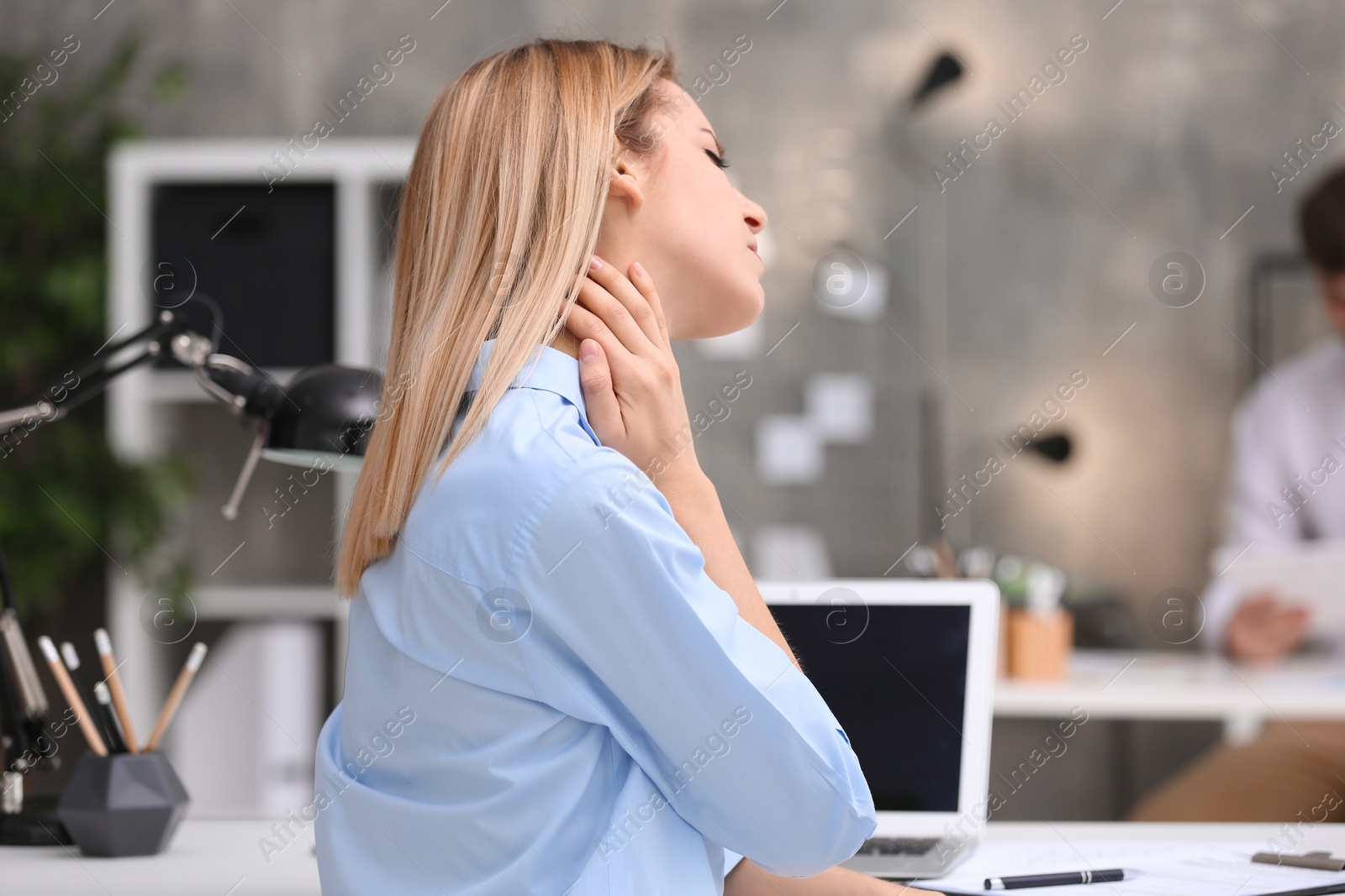 Photo of Young woman suffering from neck pain in office