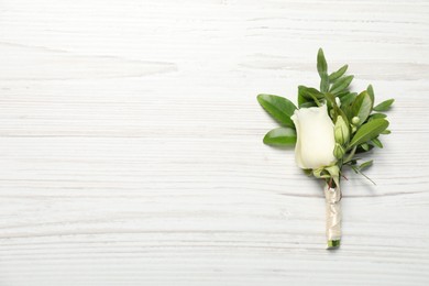 Photo of Wedding stuff. Stylish boutonniere on white wooden table, top view. Space for text