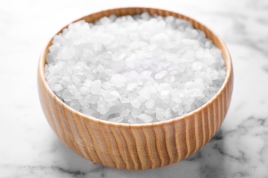 Photo of Bowl with white sea salt on marble table, closeup. Spa treatment