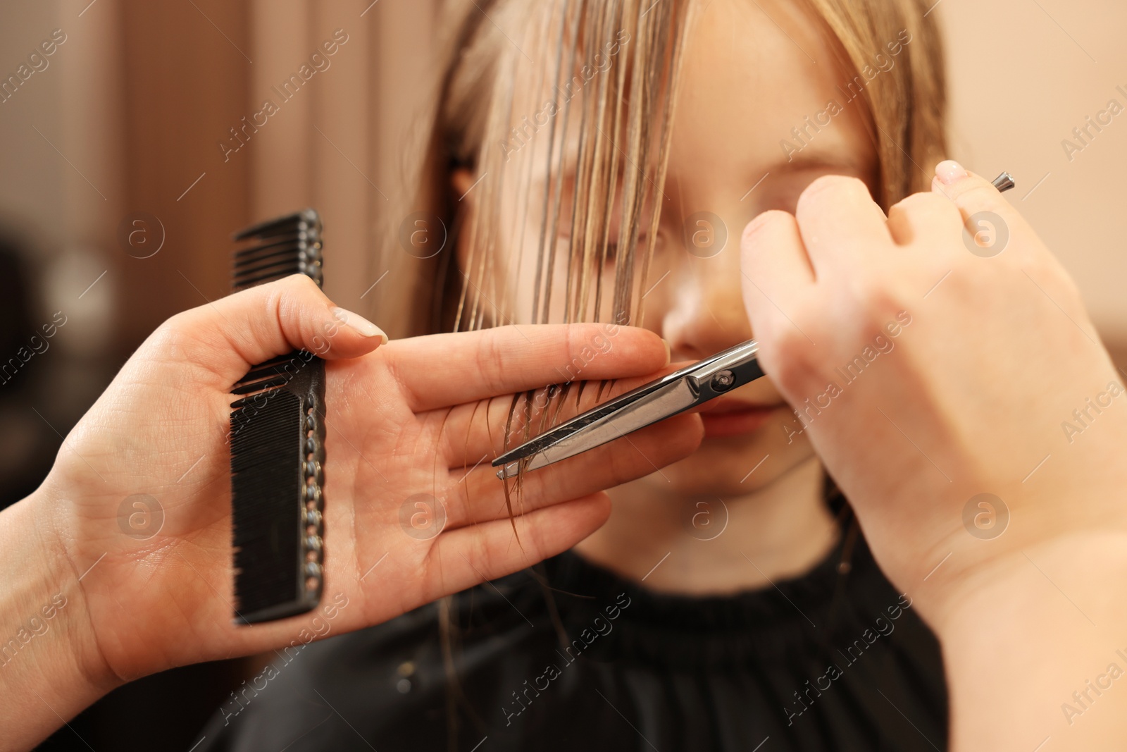 Photo of Professional hairdresser cutting girl's hair in beauty salon, closeup