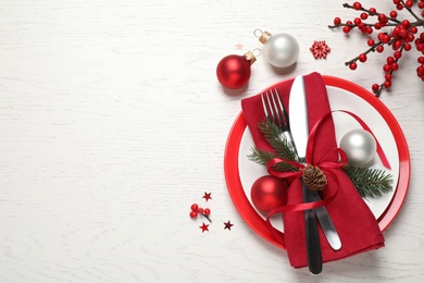 Festive table setting with beautiful dishware and Christmas decor on white wooden background, flat lay. Space for text