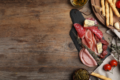 Tasty ham with other delicacies served on wooden table, flat lay. Space for text