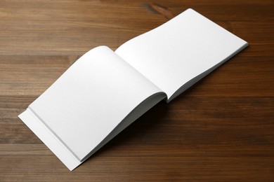 Photo of Open blank paper brochure on wooden table. Mockup for design