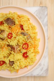 Photo of Delicious pilaf with meat on wooden table, top view