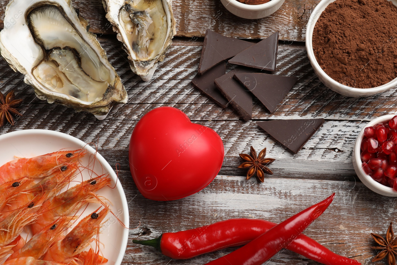 Photo of Natural aphrodisiac. Different food products and heart model on wooden table, flat lay