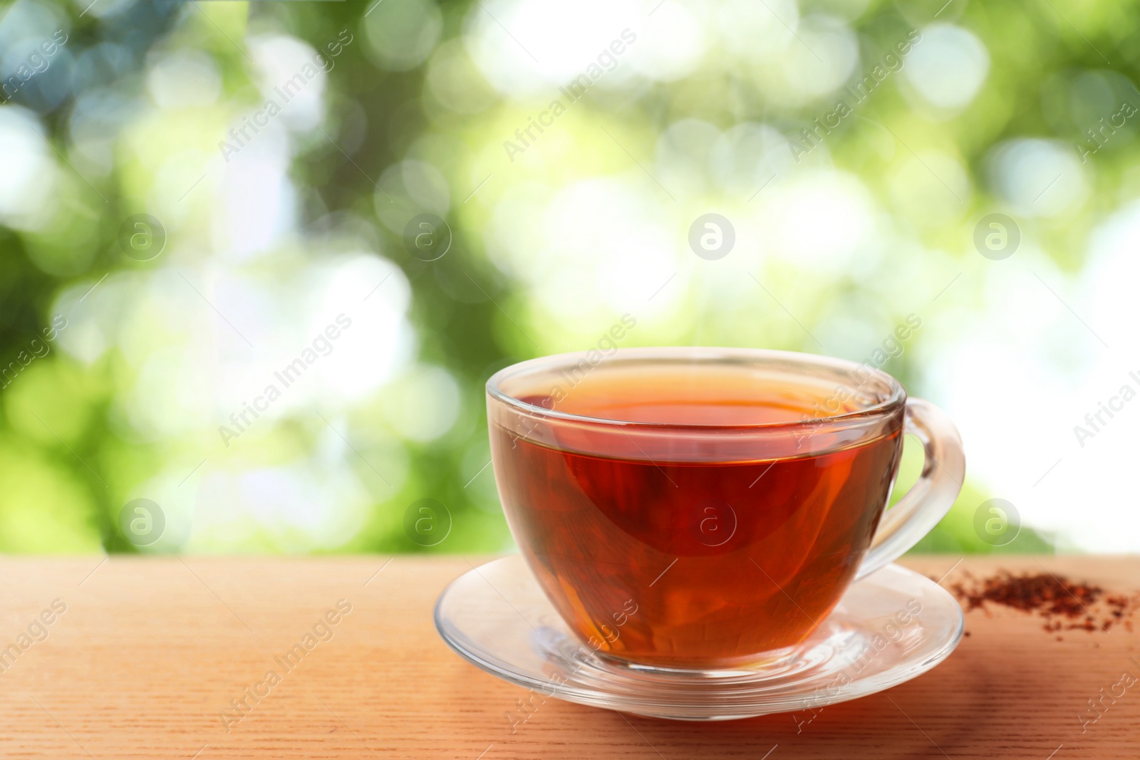 Image of Cup of hot freshly brewed rooibos tea on wooden table outdoors