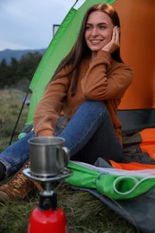 Photo of Happy young woman in camping tent outdoors