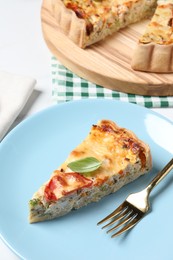 Photo of Piece of tasty quiche with chicken, cheese, basil and vegetables on white table, closeup