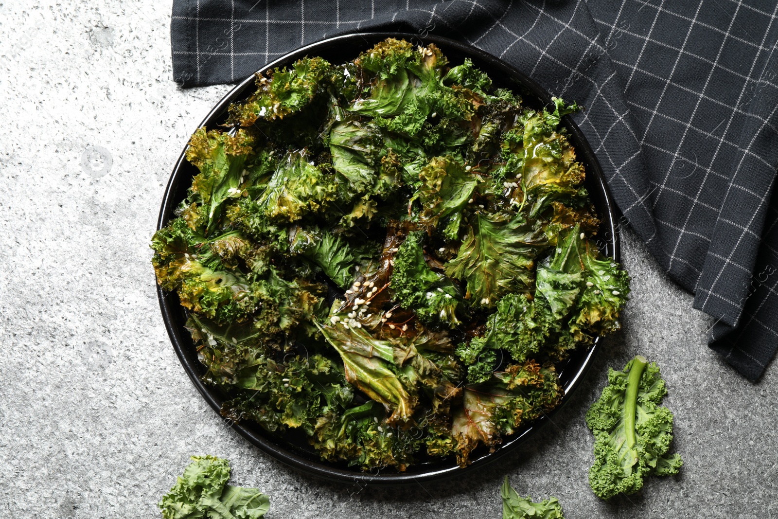 Photo of Tasty baked kale chips on grey table, flat lay