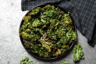 Tasty baked kale chips on grey table, flat lay