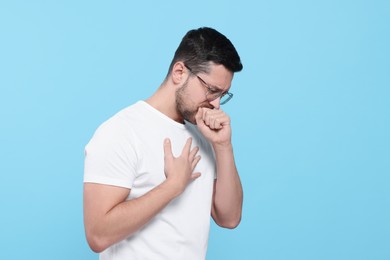 Photo of Man coughing on light blue background. Sore throat