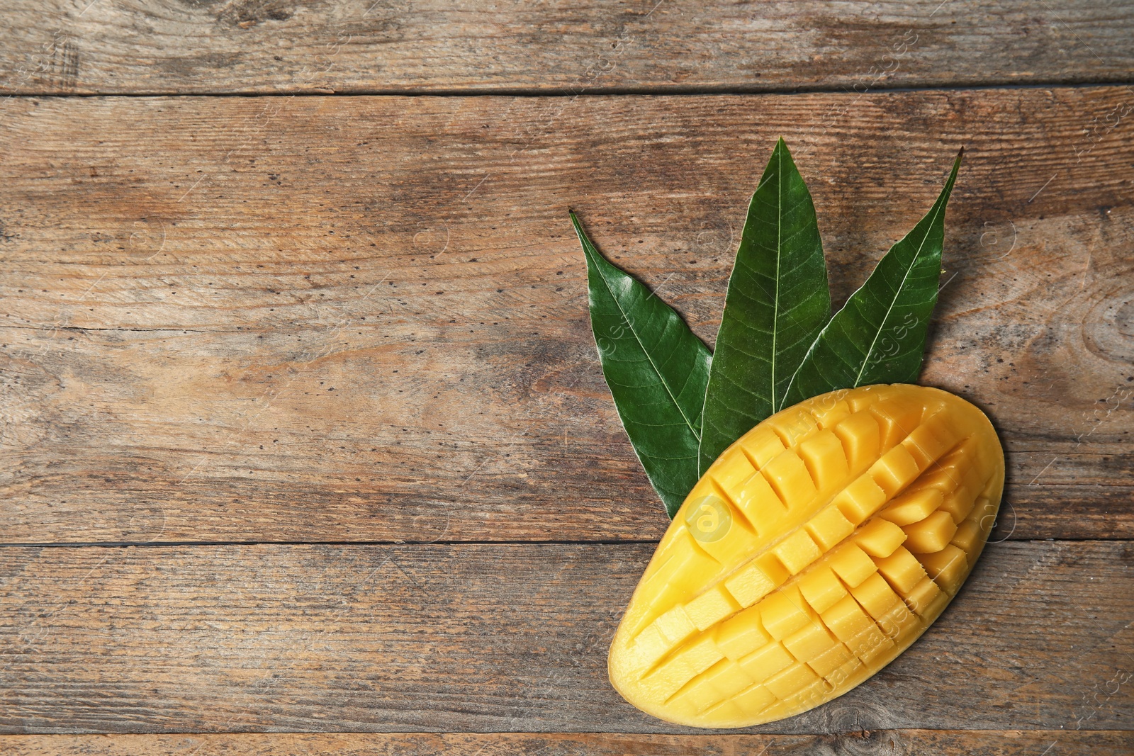 Photo of Ripe juicy mango on wooden table, top view. Space for text