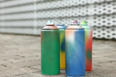 Photo of Used cans of spray paints on pavement, closeup