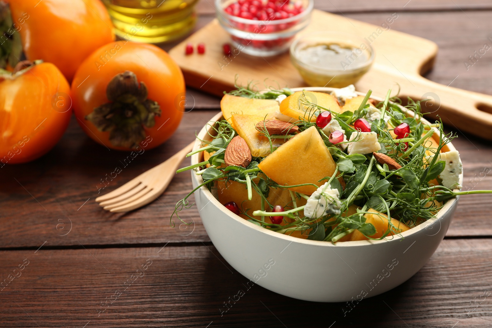 Photo of Delicious persimmon salad with pomegranate and blue cheese on wooden table