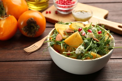 Photo of Delicious persimmon salad with pomegranate and blue cheese on wooden table