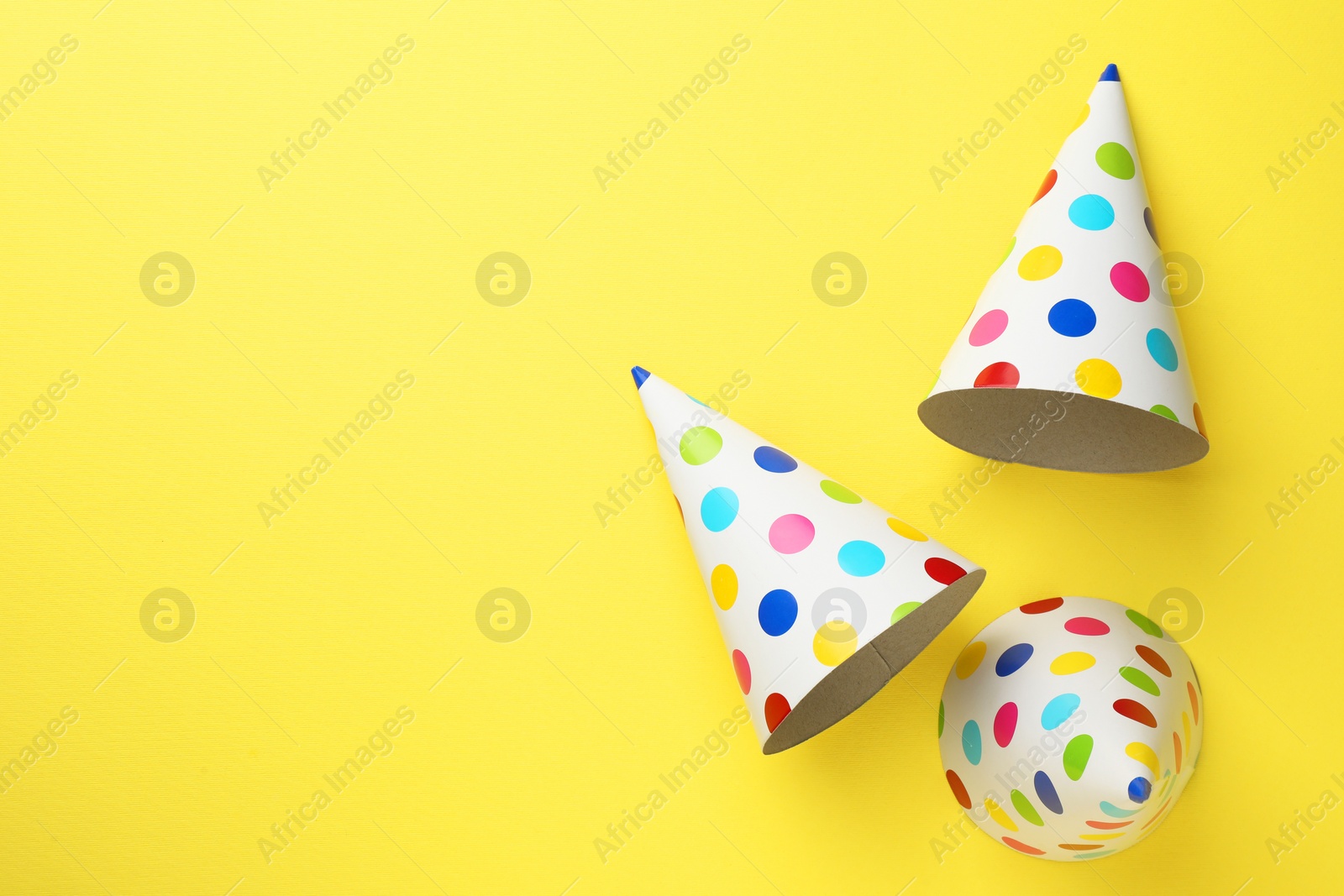 Photo of Beautiful party hats on yellow background, top view. Space for text