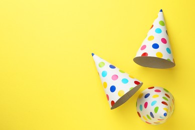 Photo of Beautiful party hats on yellow background, top view. Space for text