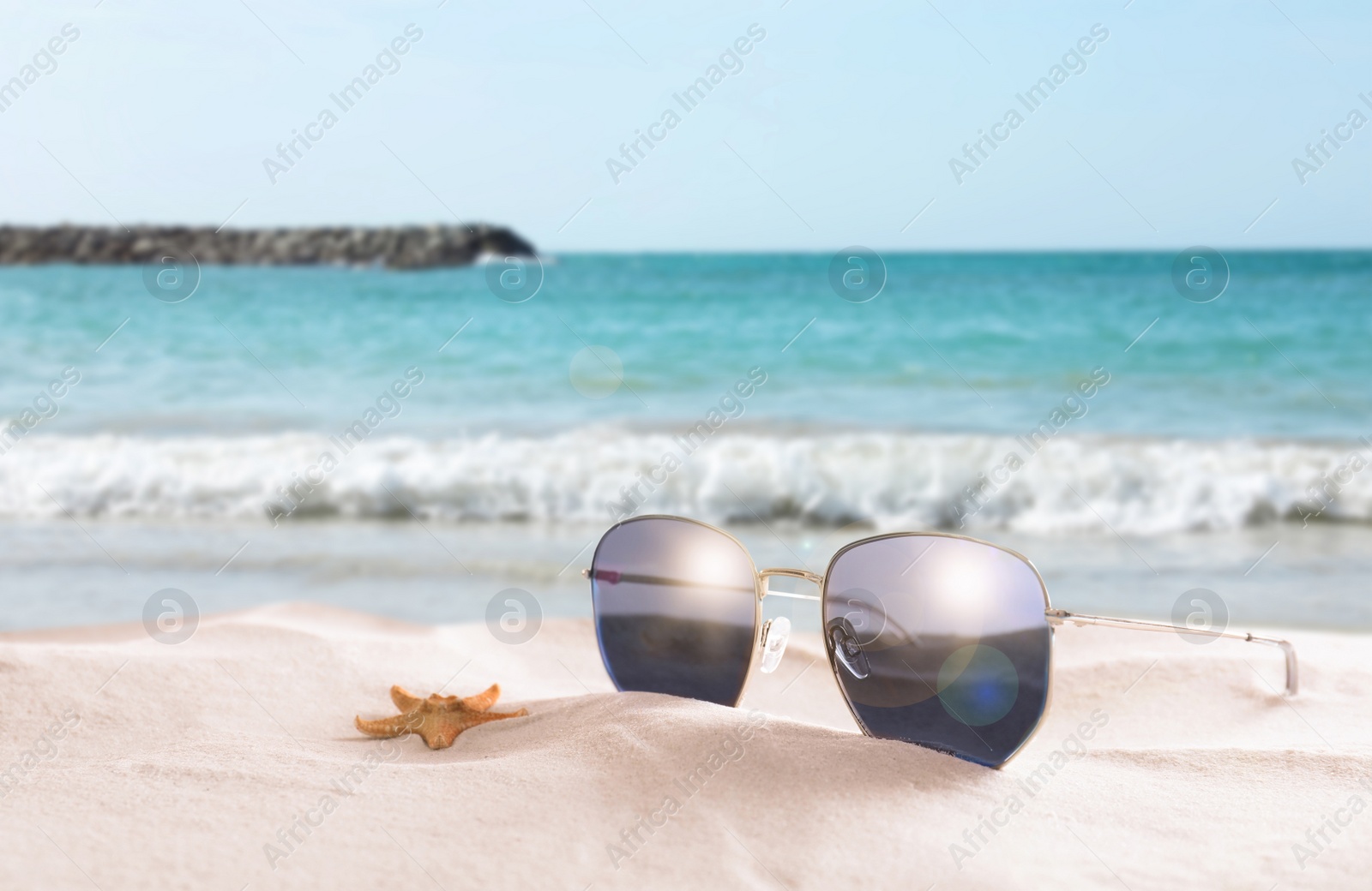 Image of Starfish and stylish sunglasses on sandy beach near sea