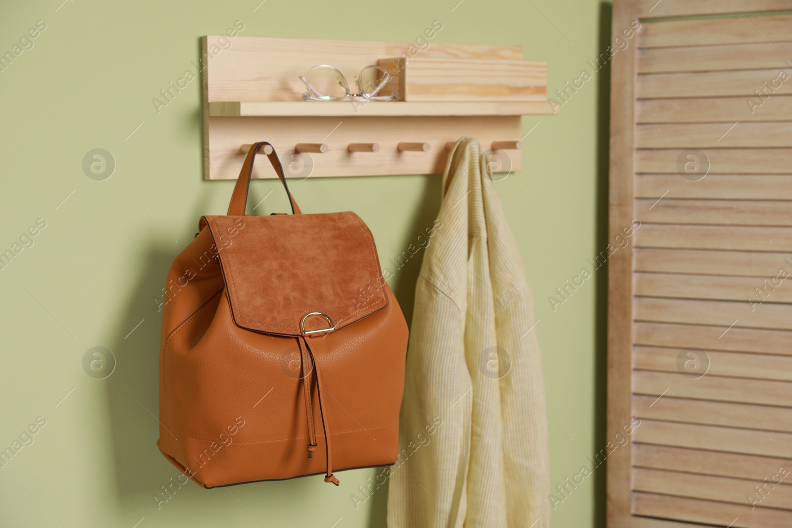 Photo of Stylish urban backpack and jacket on hanger indoors