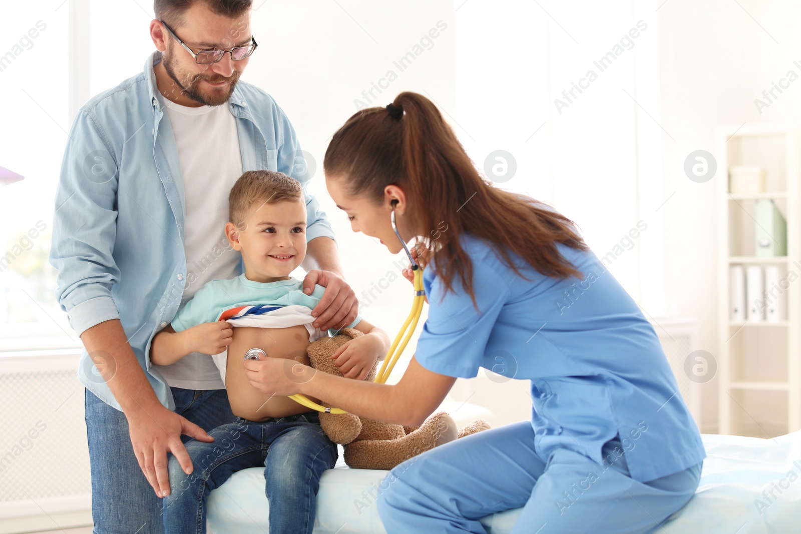 Photo of Children's doctor examining little boy with stethoscope in hospital