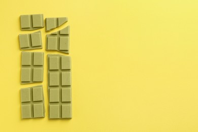 Pieces of tasty matcha chocolate bar on yellow background, top view. Space for text