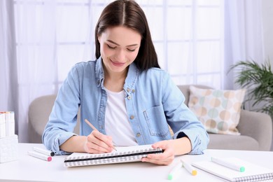 Photo of Young woman drawing in sketchbook at home