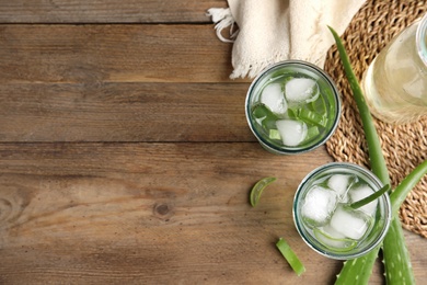 Photo of Fresh aloe drink with ice cubes on wooden table, flat lay. Space for text