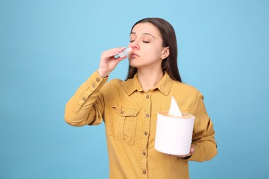 Photo of Woman using nasal spray on light blue background