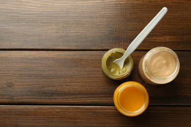 Photo of Tasty baby food in jars on wooden table, flat lay. Space for text