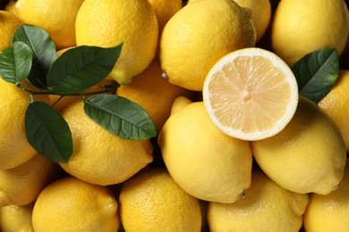 Fresh lemons and green leaves as background, top view