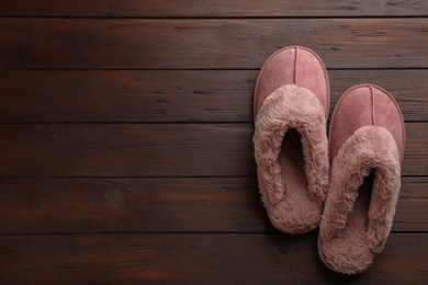 Pair of stylish soft slippers on wooden background, flat lay. Space for text