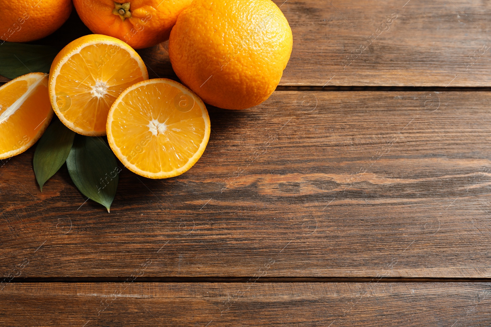 Photo of Fresh oranges with leaves on wooden background, top view. Space for text