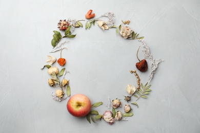 Photo of Dried flowers, leaves and apple arranged in shape of wreath on light grey background, flat lay with space for text. Autumnal aesthetic