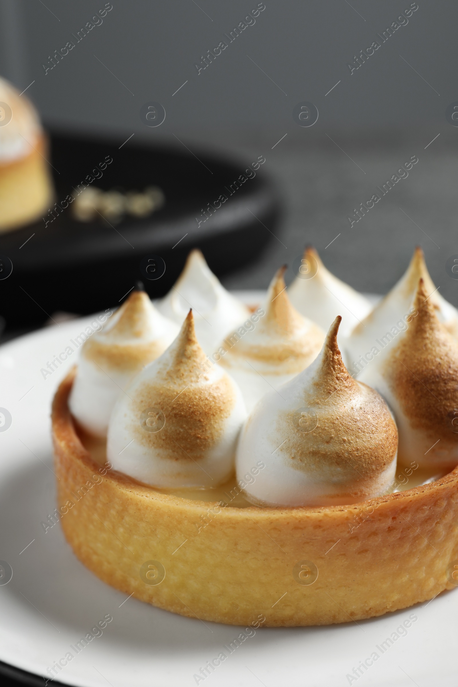 Photo of Tartlet with meringue on plate, closeup. Tasty dessert