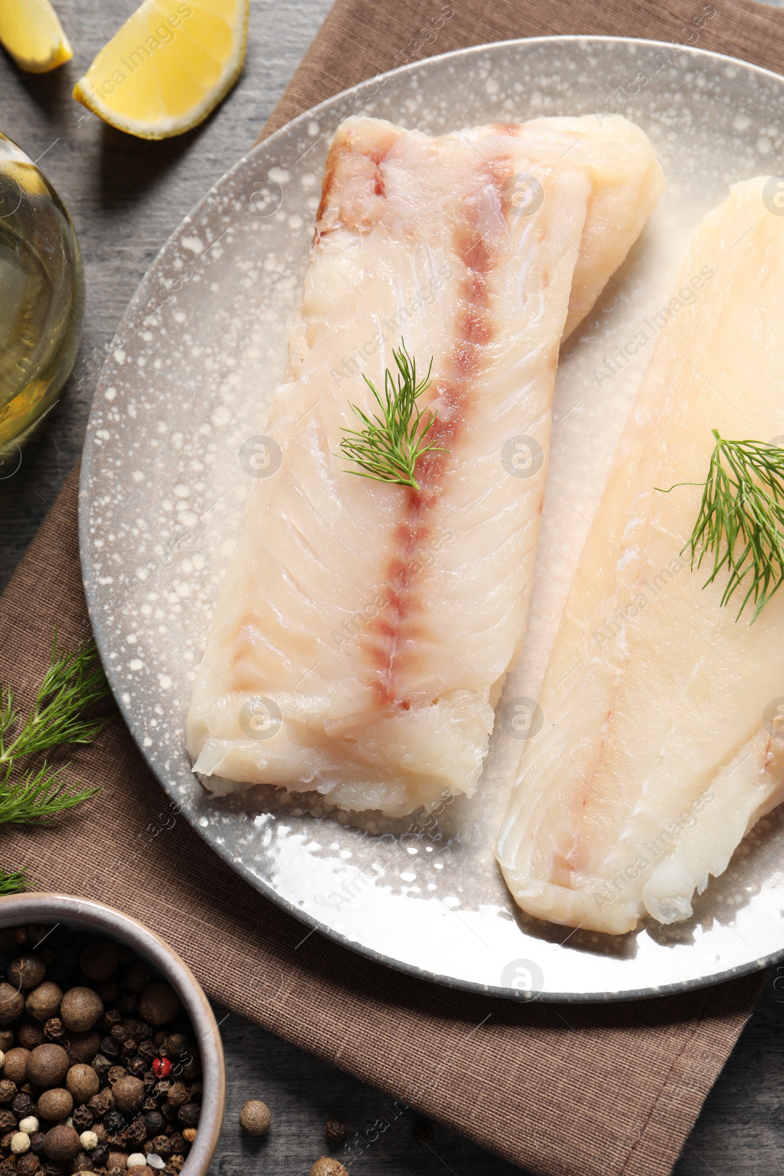 Photo of Pieces of raw cod fish, dill and peppercorns on table, top view