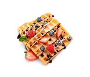 Photo of Yummy waffles with berries and chocolate syrup on white background, top view