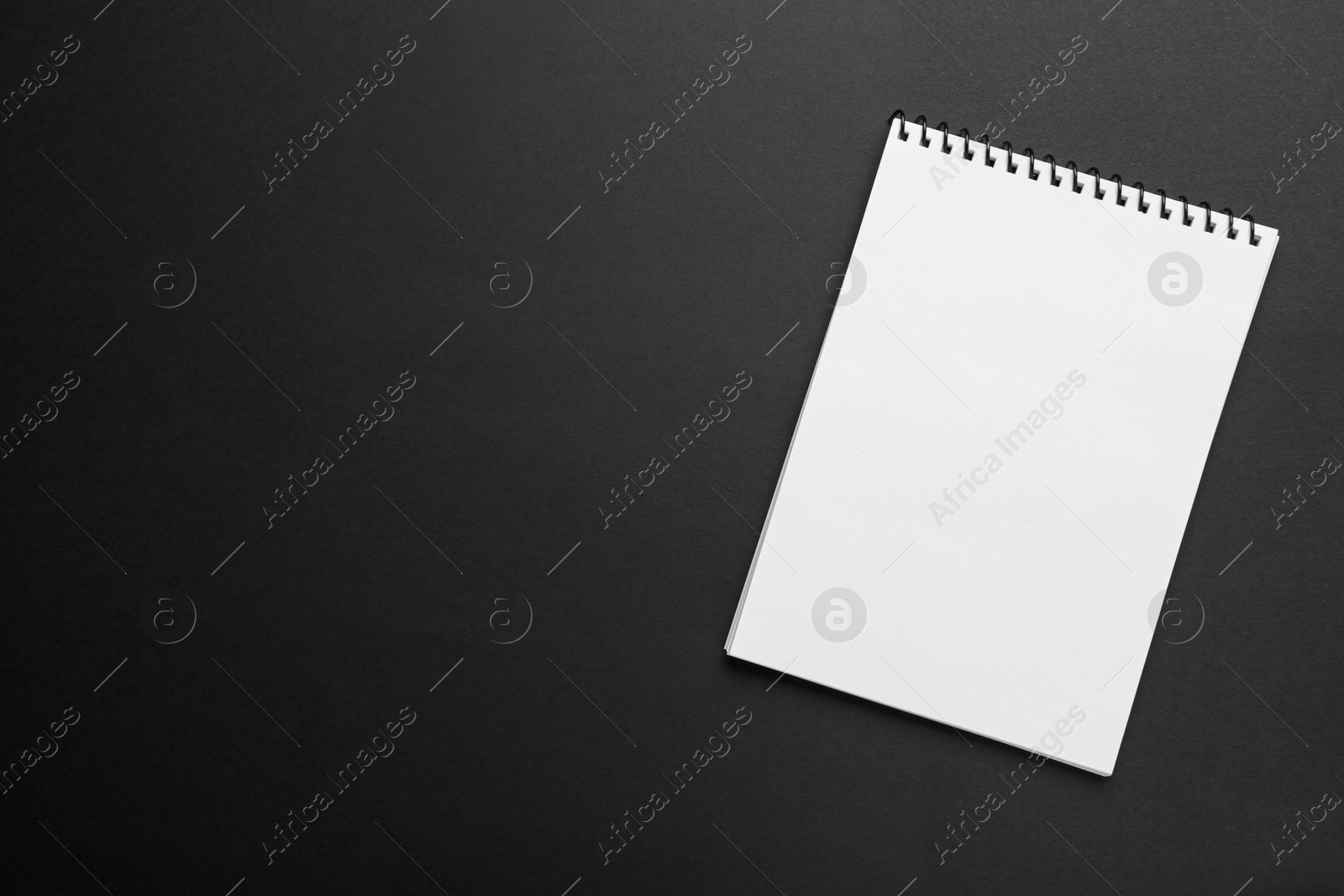 Photo of One notebook on black background, top view. Space for text