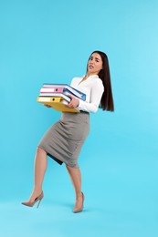 Photo of Stressful woman with folders walking on light blue background