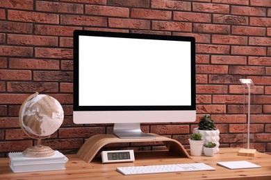 Photo of Stylish workplace with modern computer near brick wall indoors. Space for text