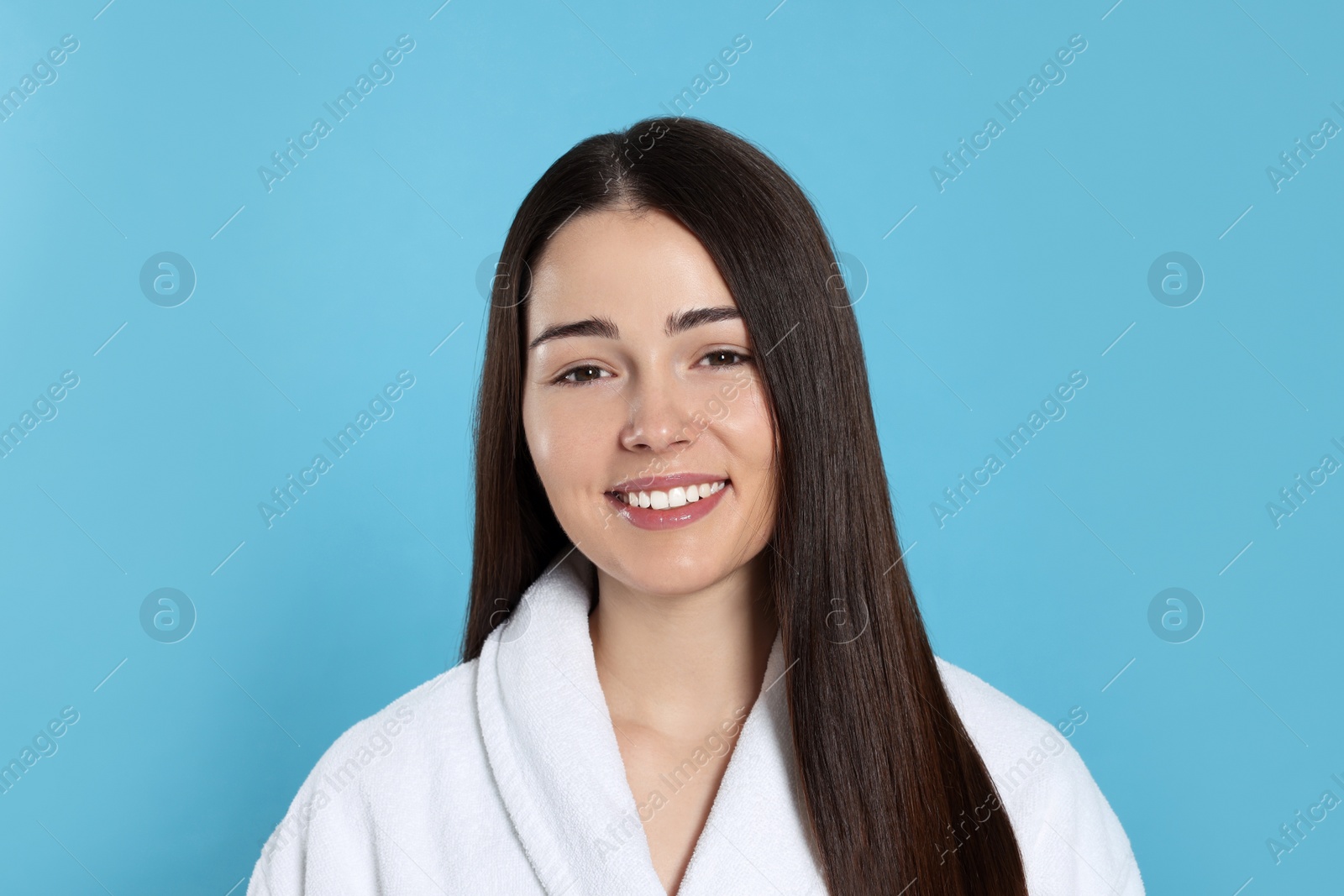 Photo of Portrait of attractive young woman in bathrobe on light blue background. Spa treatment