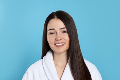 Portrait of attractive young woman in bathrobe on light blue background. Spa treatment